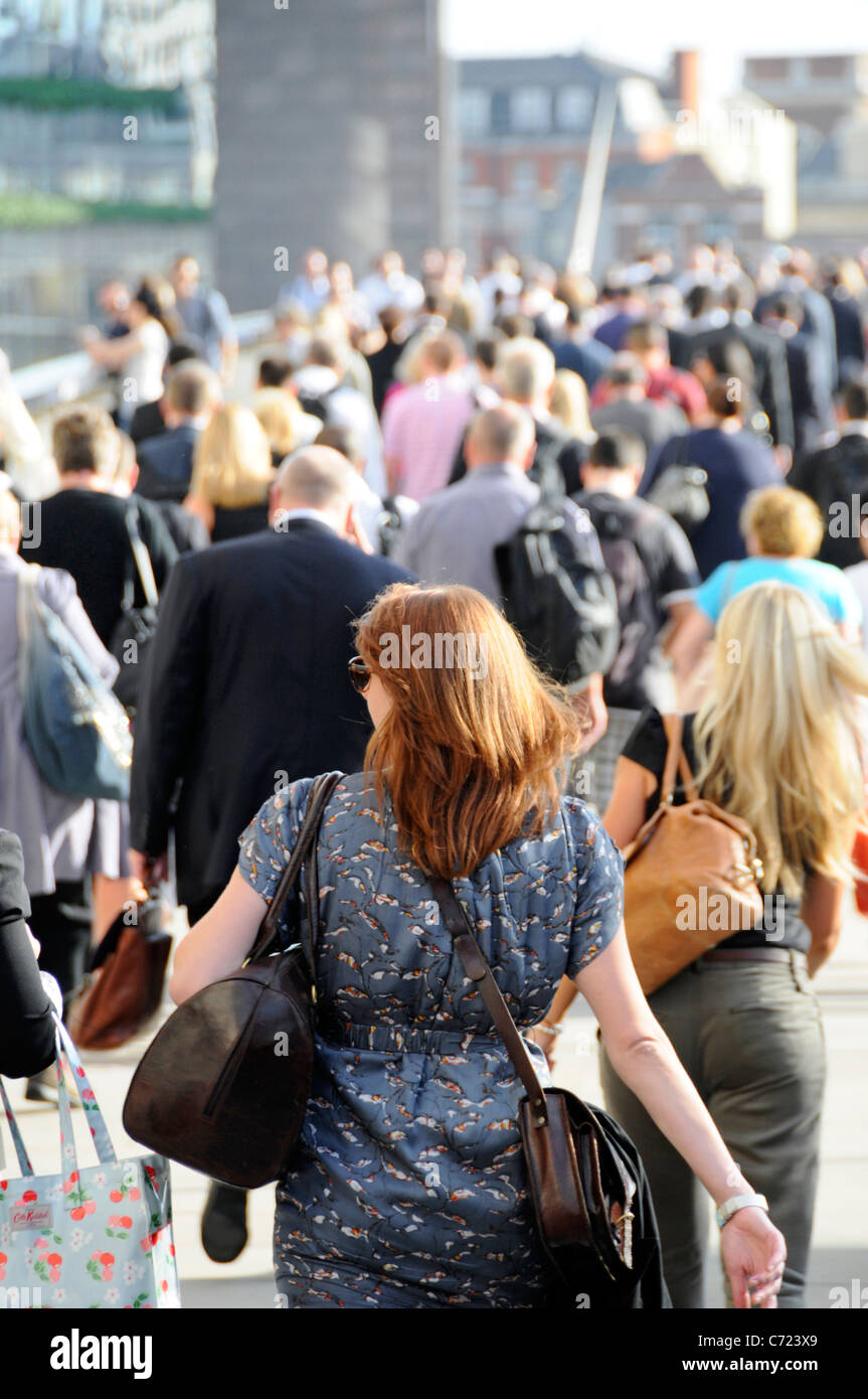 People on London Bridge backs of men & women office workers walking towards London Bridge station during sunny summer evening rush hour England UK Stock Photo
