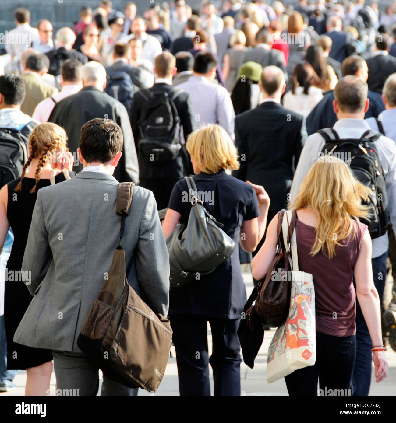 Back view office workers walking on crowded bridge towards London Bridge railway station summertime evening rush hour going home from work England UK Stock Photo