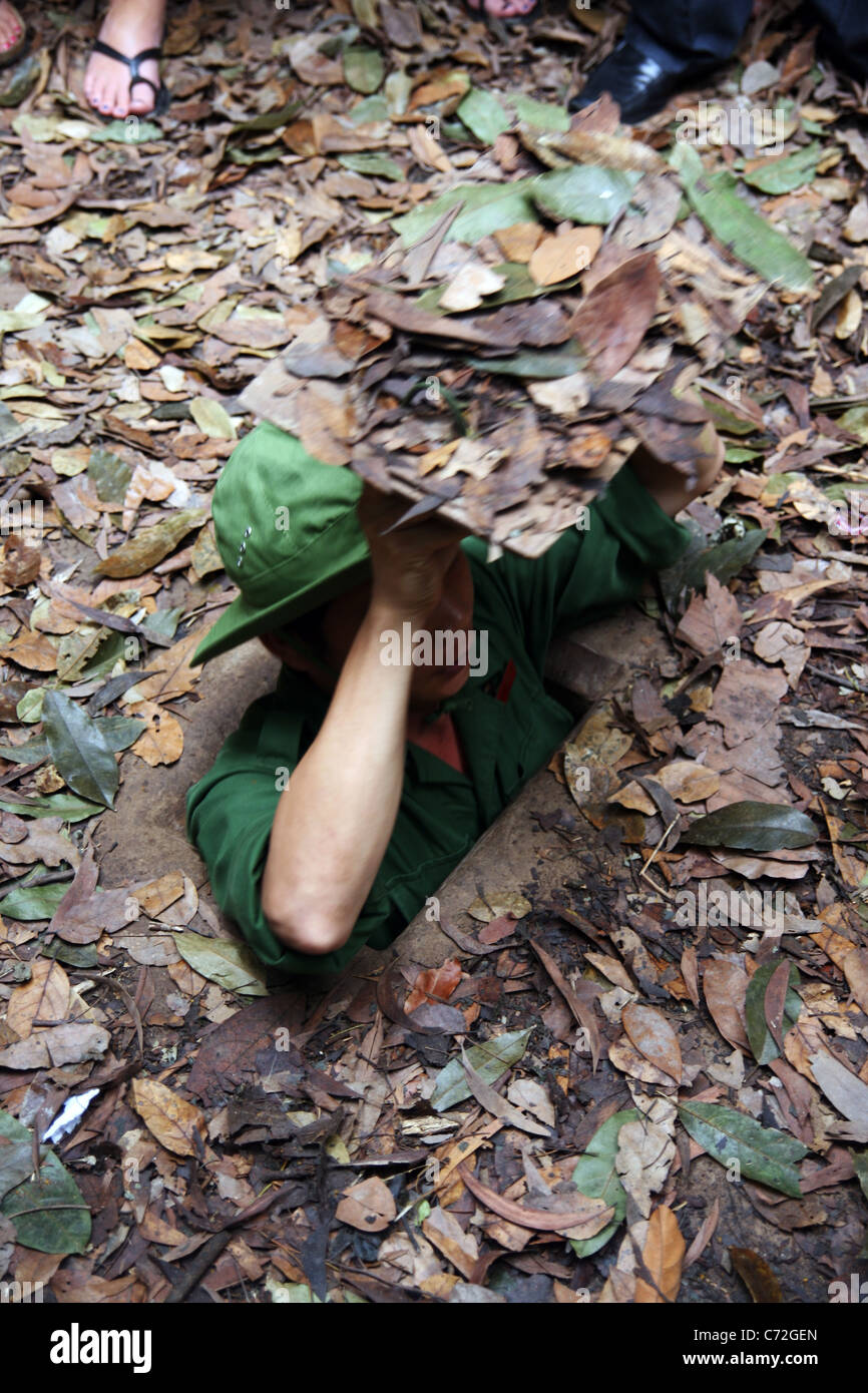 Vietnamese guide showing a tunnel entrance used in the Vietnam War. Cu Chi, Vietnam Stock Photo
