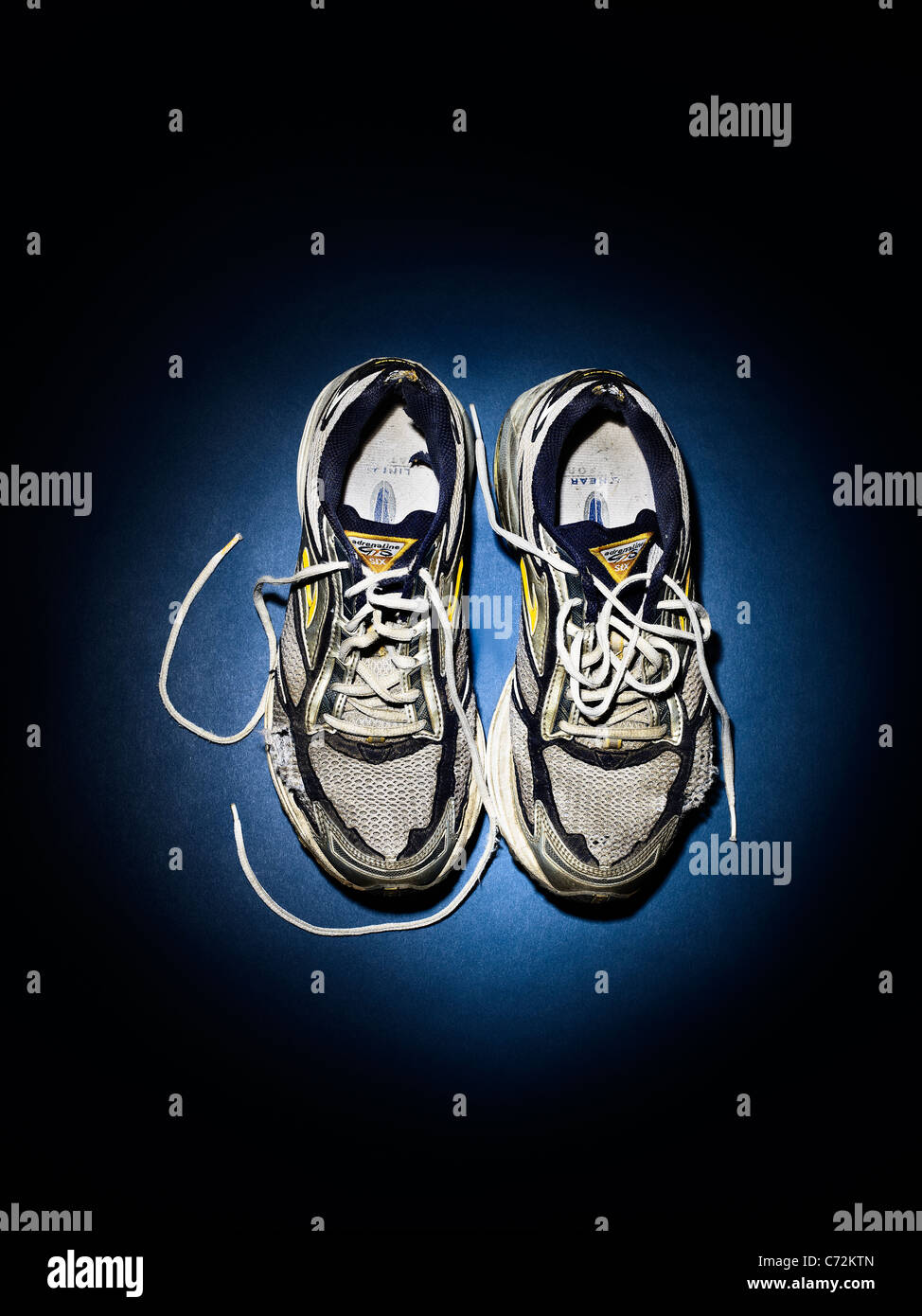 Old running shoes, trainers in a spotlight Stock Photo