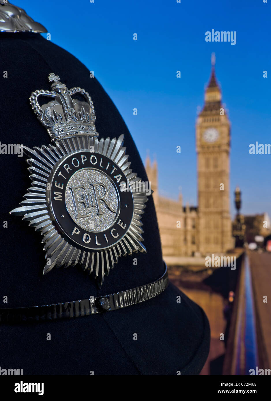 Metropolitan police constable helmet and badge with Houses of Parliament & River Thames Westminster behind Law Politics Recruitment Concept London UK Stock Photo