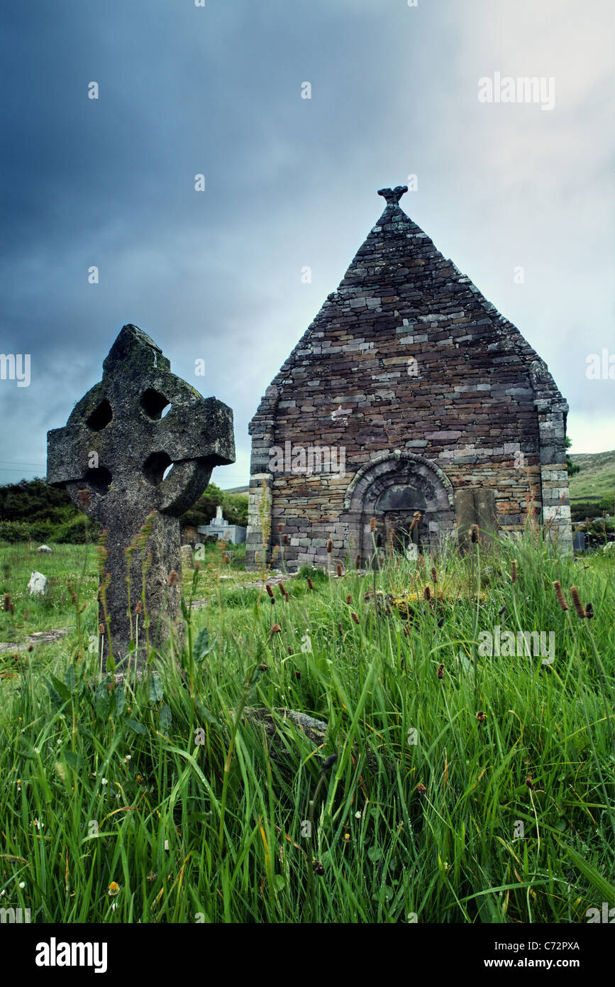 Cross headstone in front of ruined Norman church of Kilmalkedar (Cill Mhaoilcheadair), Dingle Peninsula, County Kerry, Ireland Stock Photo