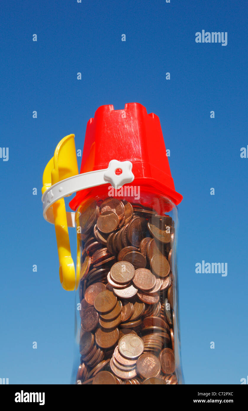Euro coins in jar with bucket and spade on top. Holiday money concept image Stock Photo