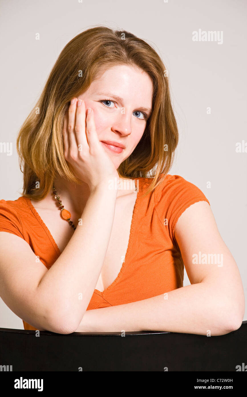 Young woman sitting, resting her head in her hand Stock Photo