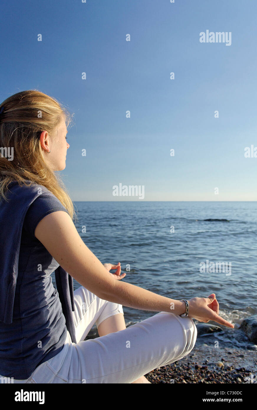 Woman meditating on the beach Stock Photo