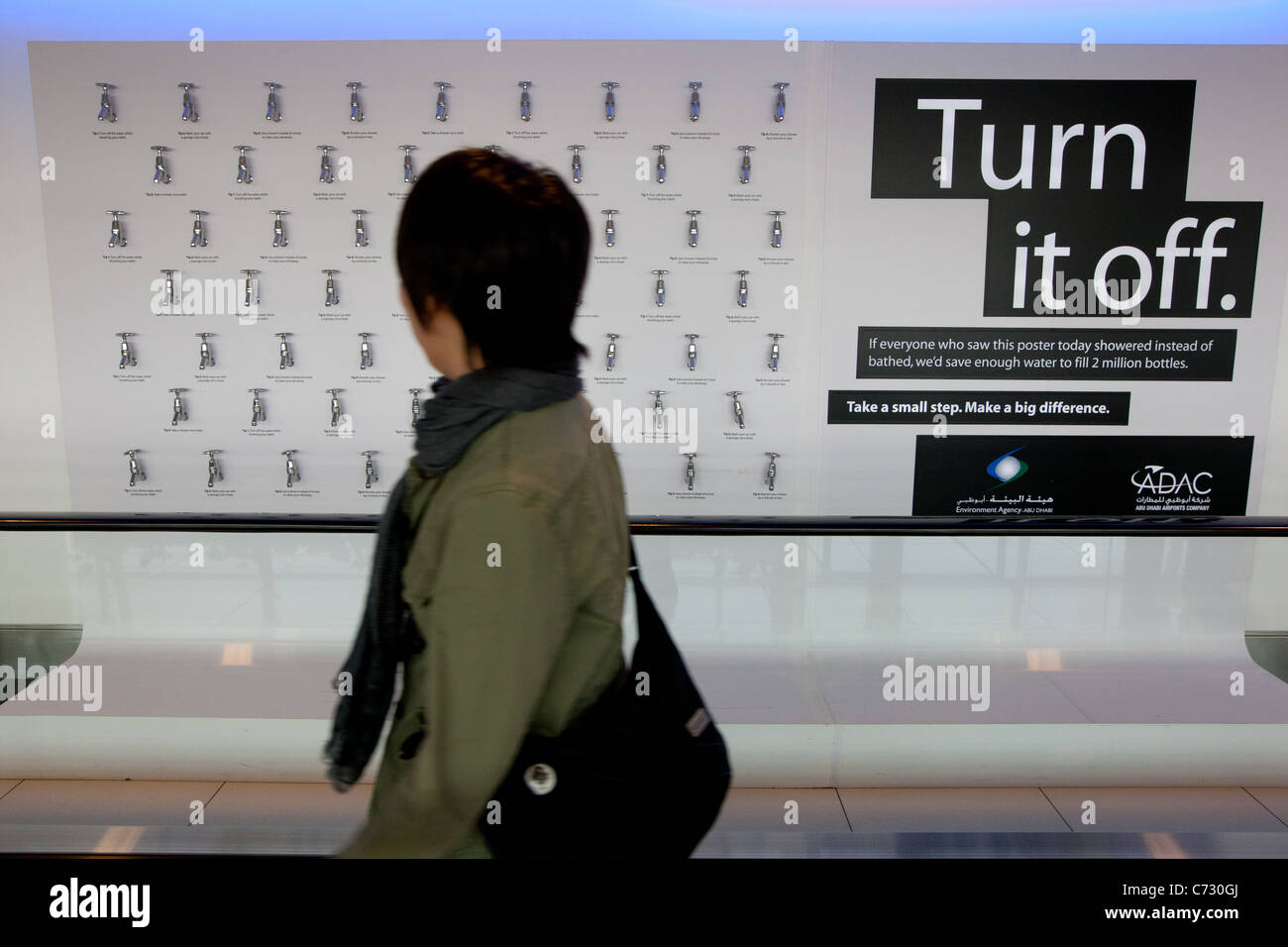 Adverts requesting the turning off of water taps to conserve water supplies, in Abu Dhabi airport, in the United Arab Emirates, Stock Photo