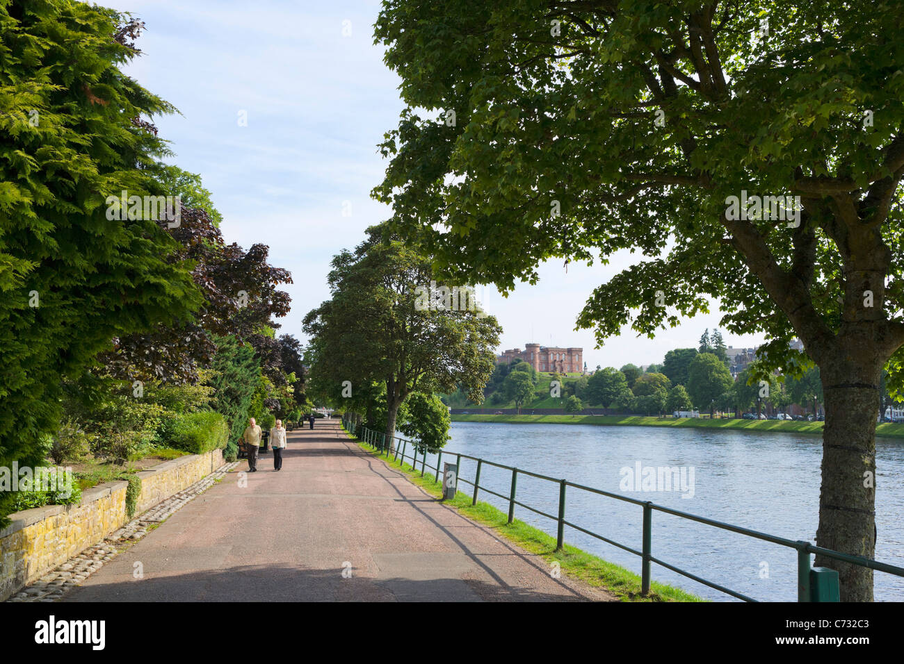 Elderly couple walking along a path on the banks of the River Ness with the Castle in distance, Inverness, Highland, Scotland Stock Photo