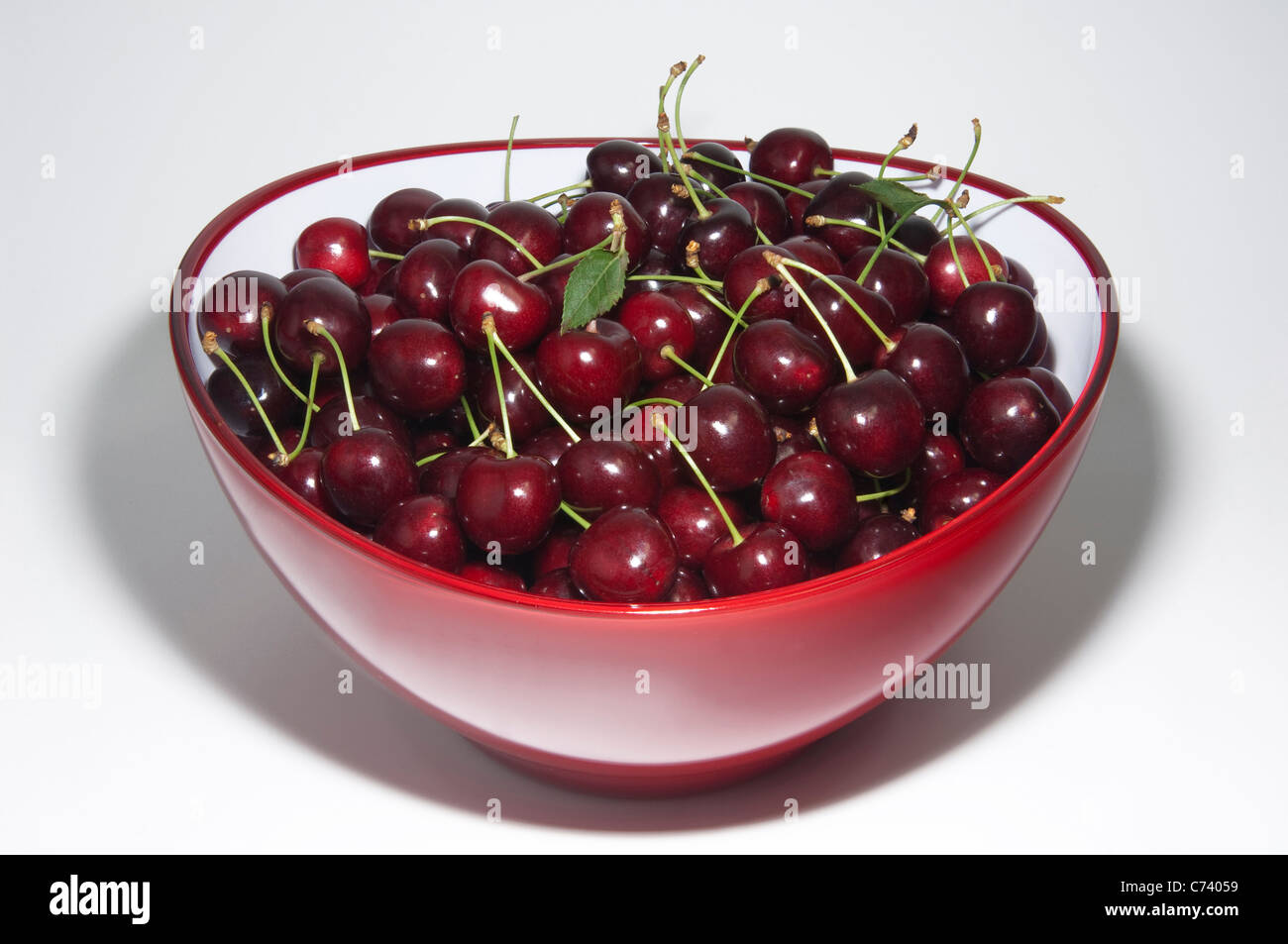 Sweet Cherry (Prunus avium). Ripe cherries in a bowl. Studio picture against a white background. Stock Photo