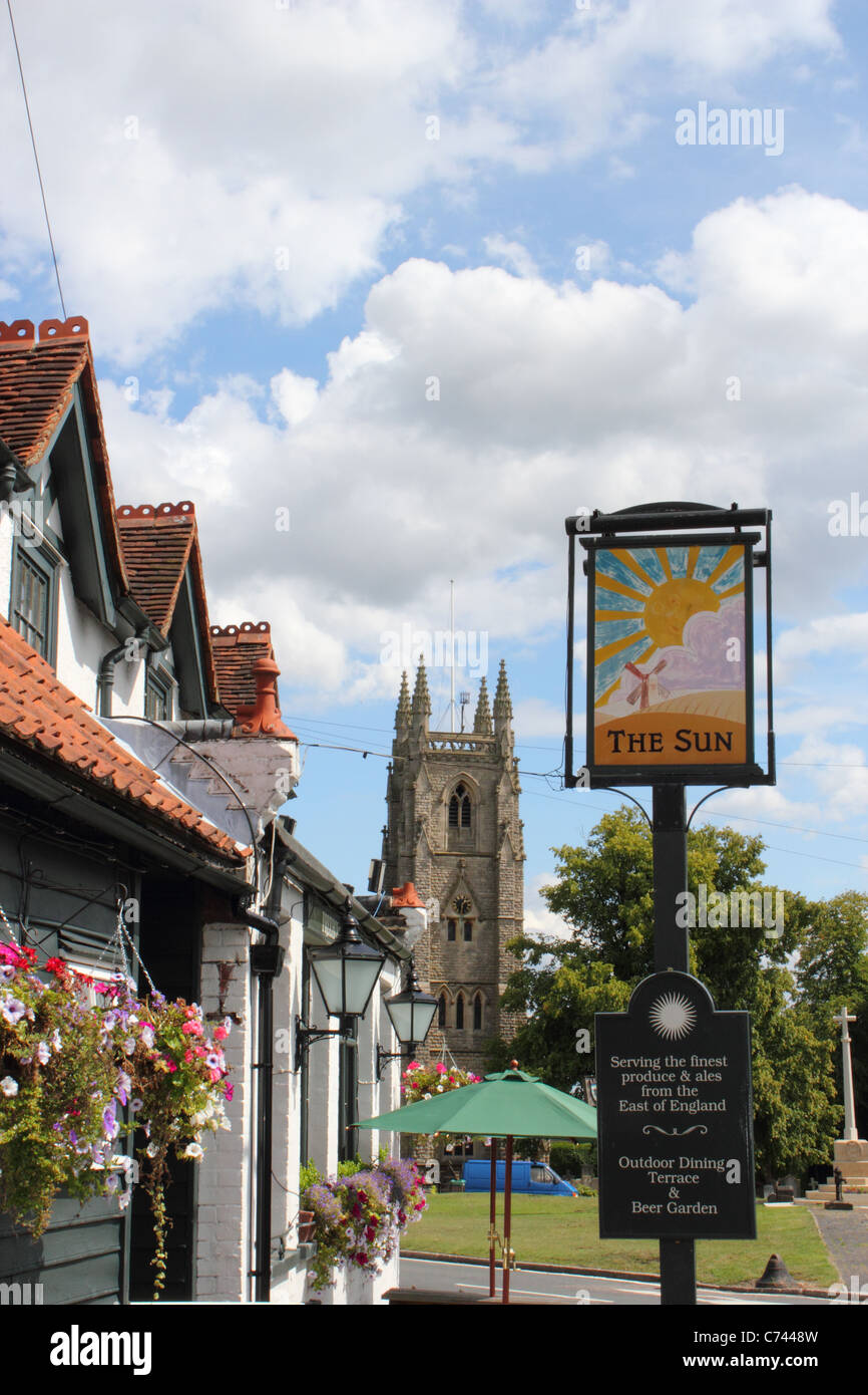 The sign of the Sun pub with St Thomas a Becket Church in background – Northaw Village, Hertfordshire during summer. Stock Photo