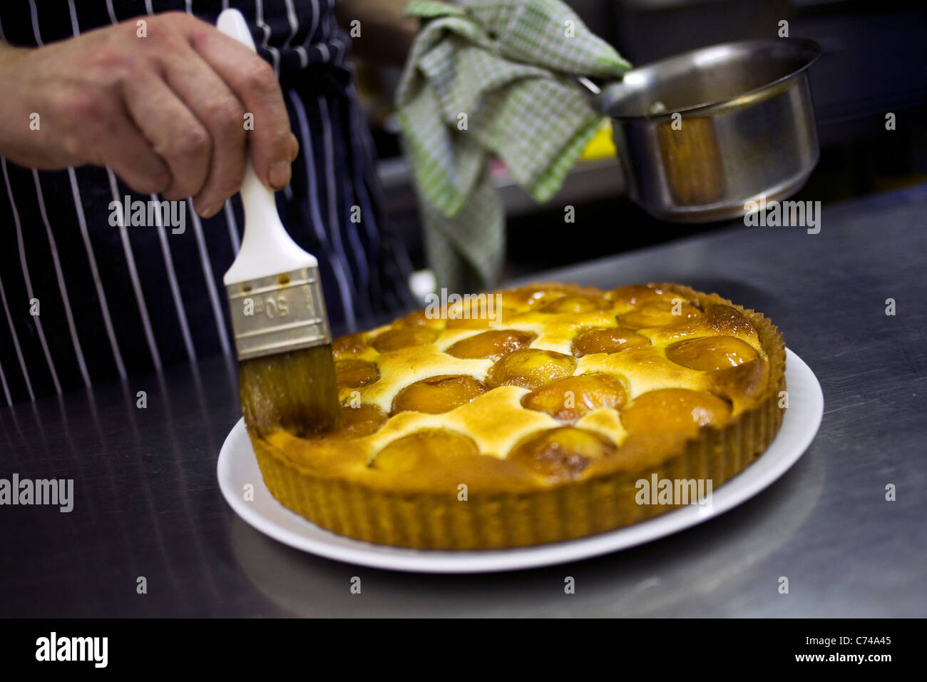 A chef glazing an apricot tart. Stock Photo