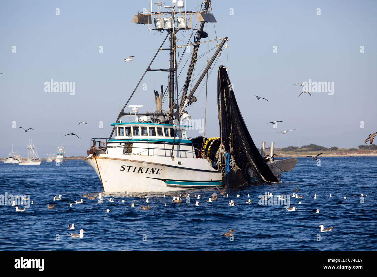 A fishing boat heads out of Monterey harbor - California. Stock Photo