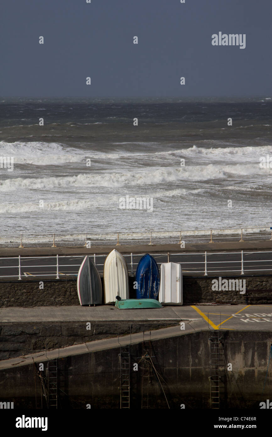 Dingies propped against a harbour wall as the tail end of Hurricane Katina begins to reach the UK coast Stock Photo