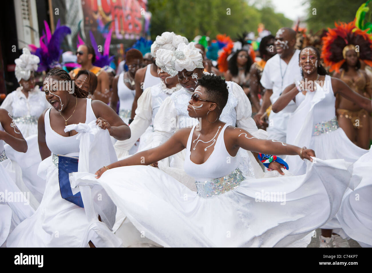 A group of parade participants in festive attire dance along the route