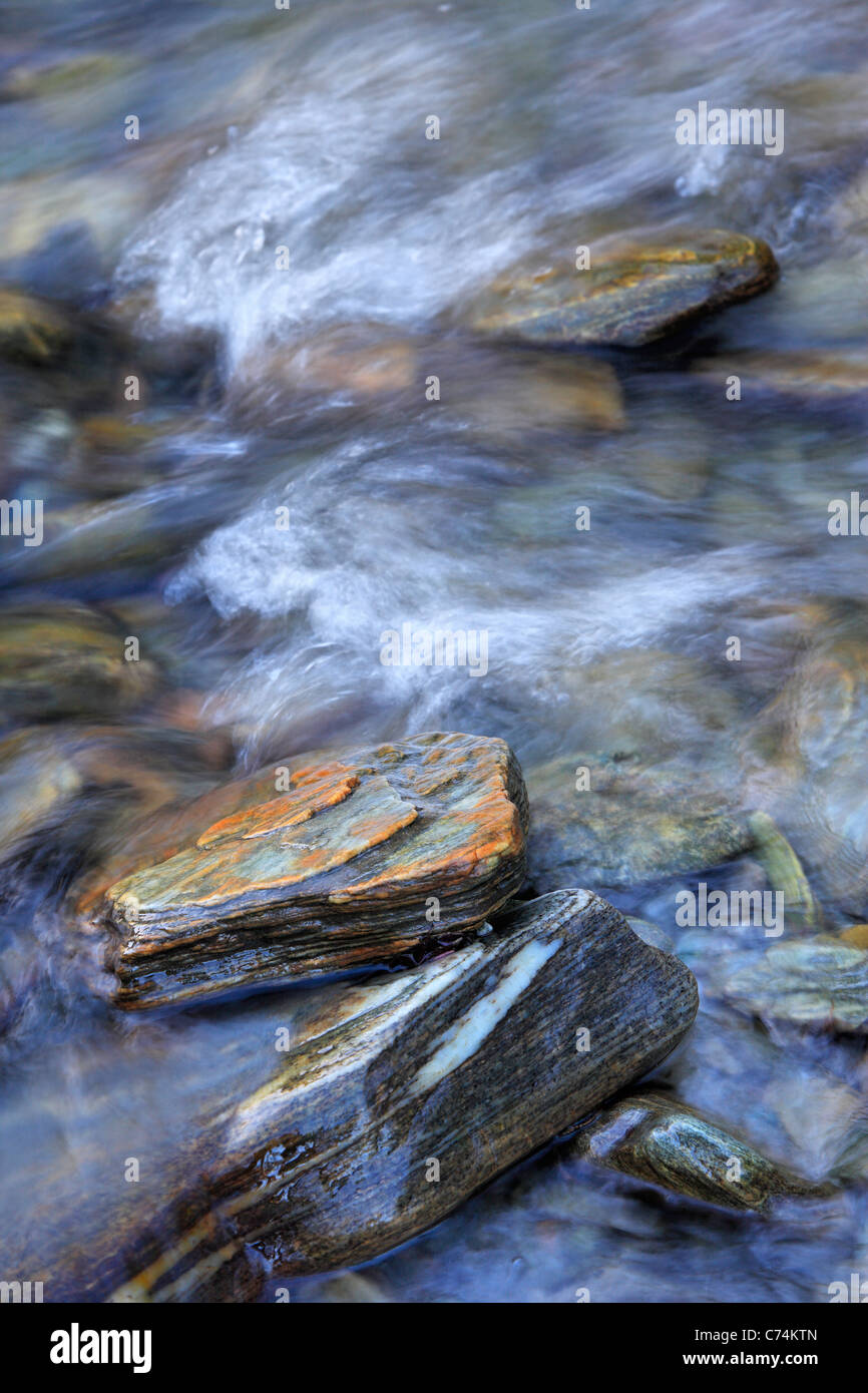 Water flowing amidst the colorful rocks of the Haast River in Haast Pass, New Zealand Stock Photo