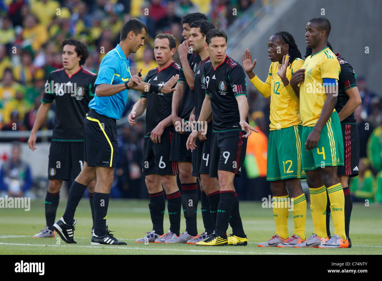 Referee Ravshan Irmatov directs South African and Mexican players for a free kick during the opening match of the 2010 World Cup Stock Photo