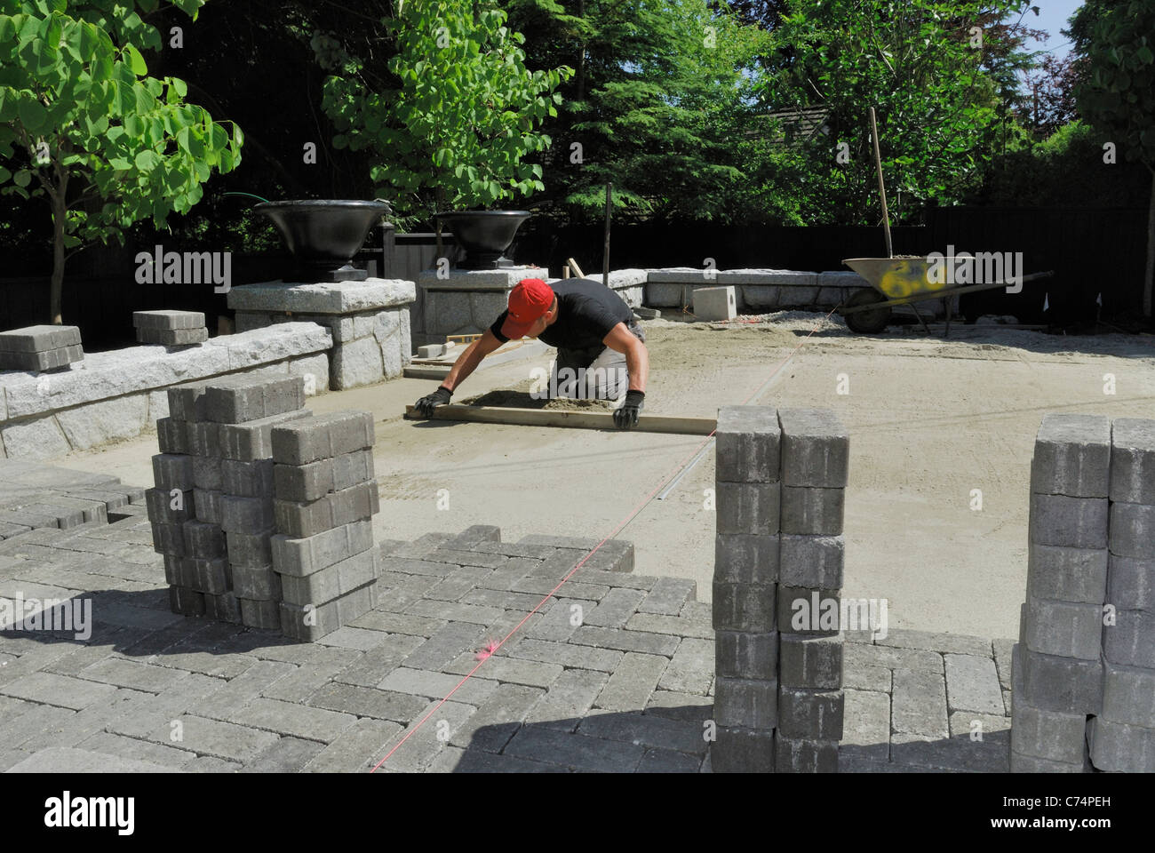 Residential construction worker laying concrete paving stones in sand. Stock Photo