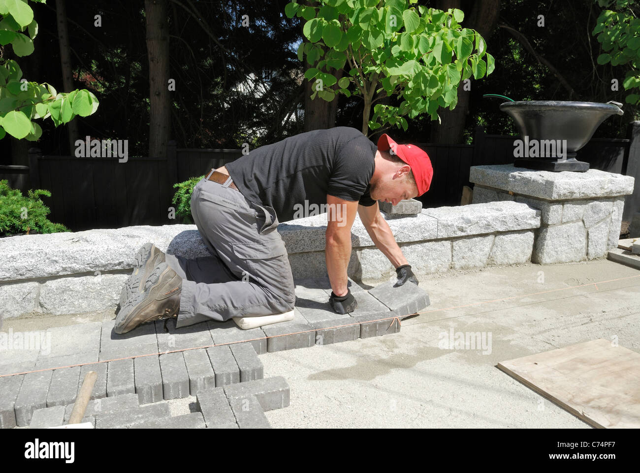 Residential construction worker laying concrete paving stones in sand. Stock Photo
