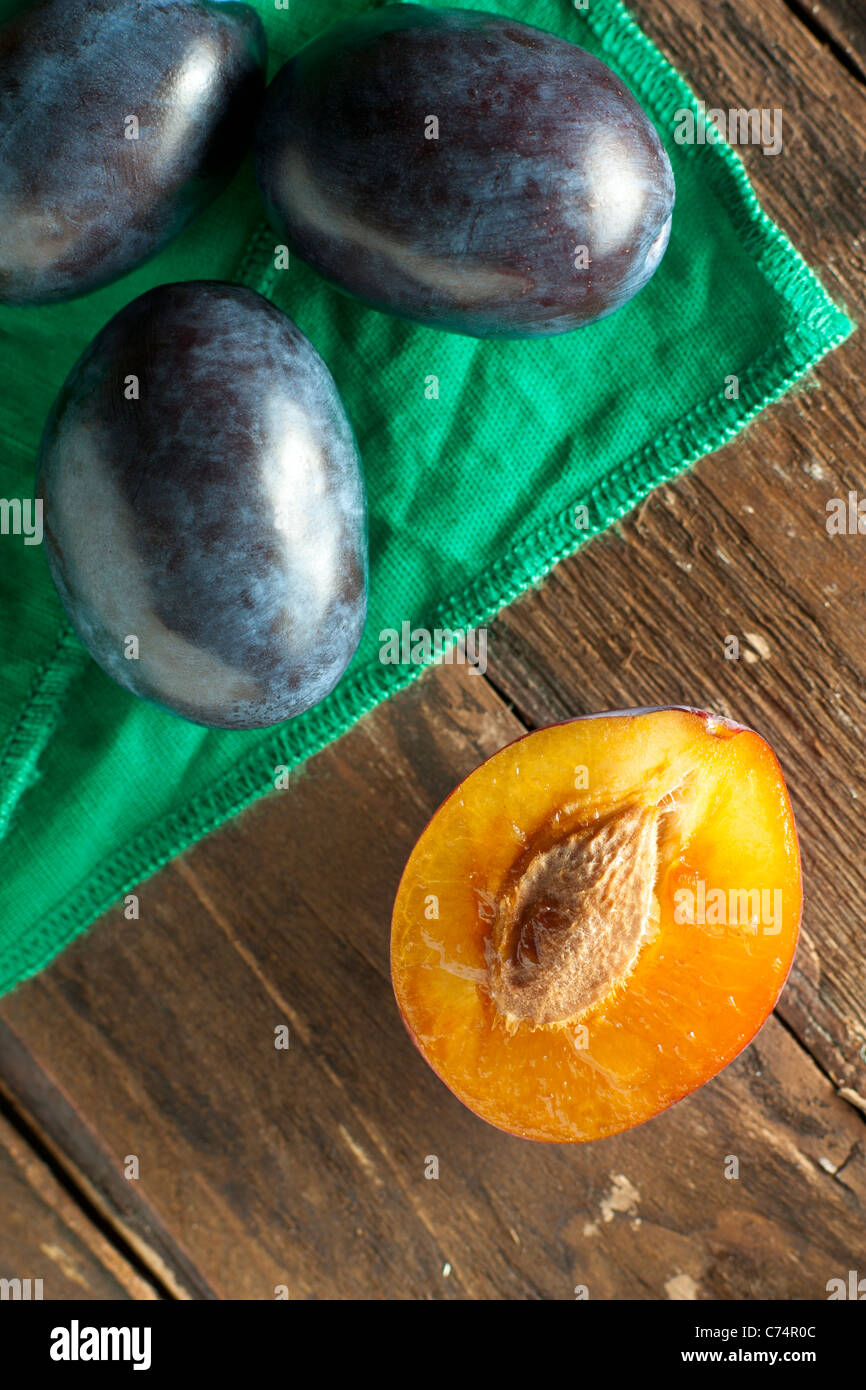 Halved Plums with Green Napkin on Wood Stock Photo