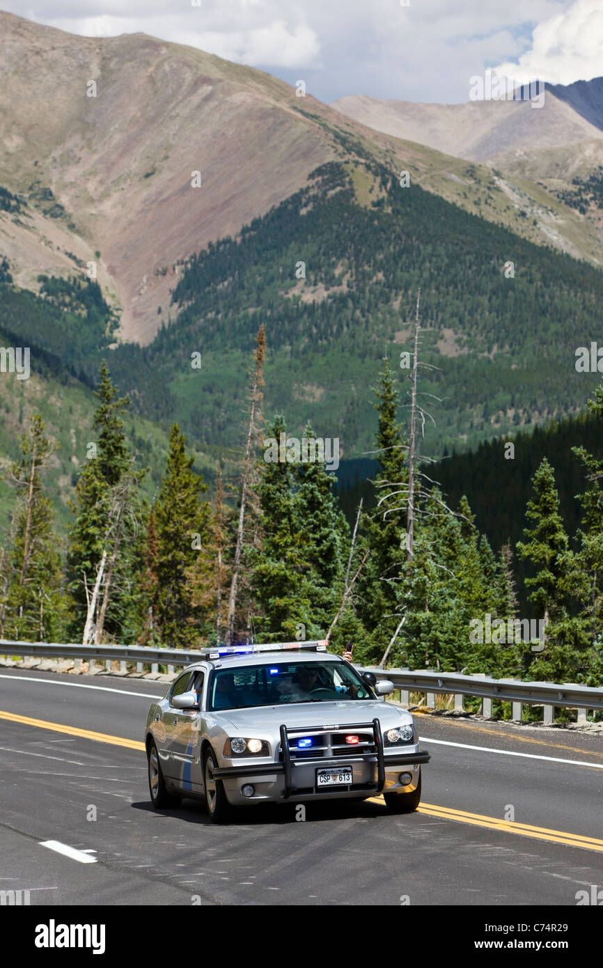 Colorado State Police car leading professional cyclists in a race over Monarch Pass in Stage 1 of the USA Pro Cycling Challenge Stock Photo