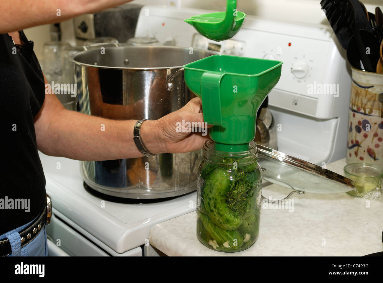 Adding the brine to a jar of pickles before sealing it Stock Photo Alamy
