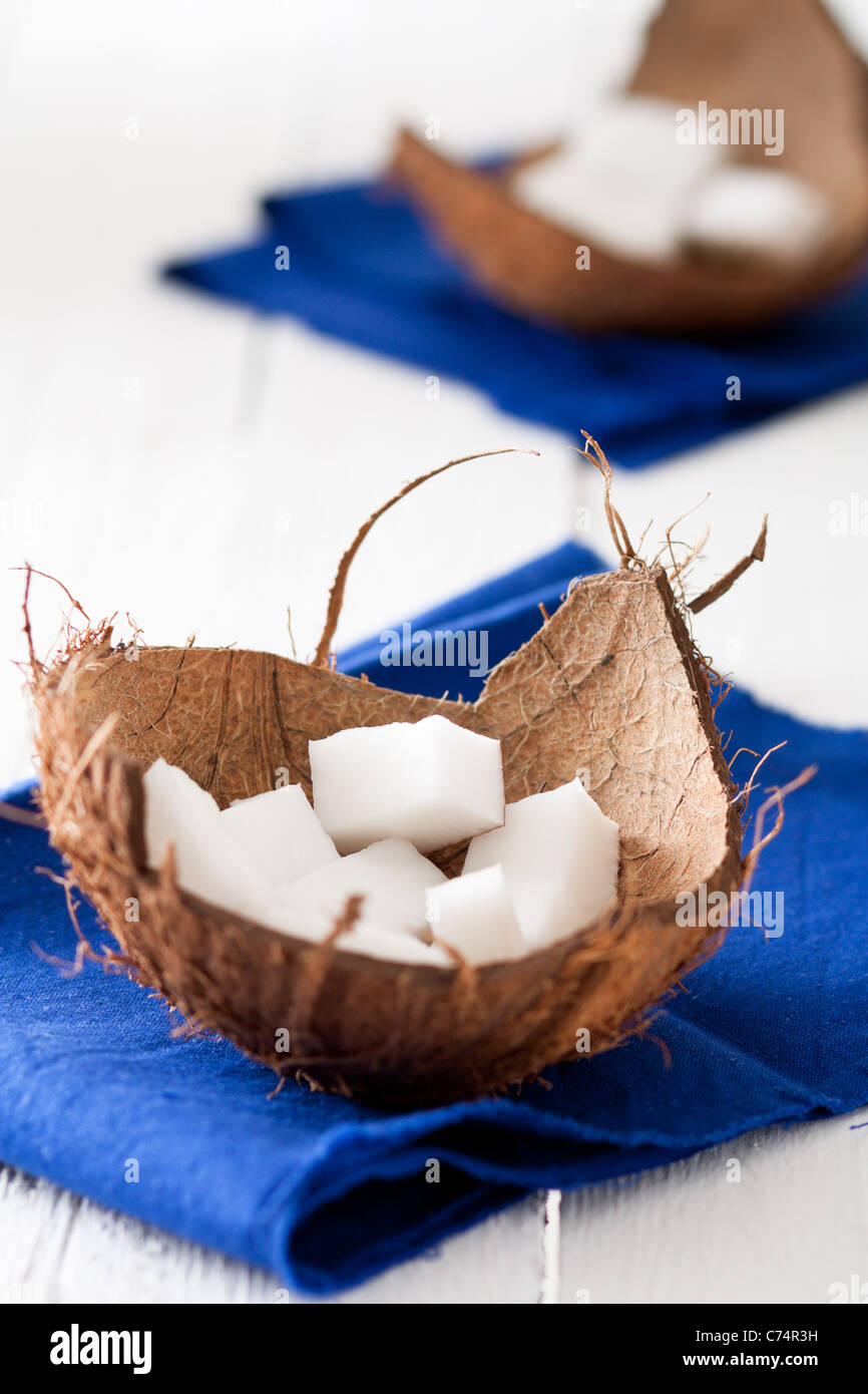 Coconut Pieces in a Shell, with Blue Napkin on White Wood Stock Photo
