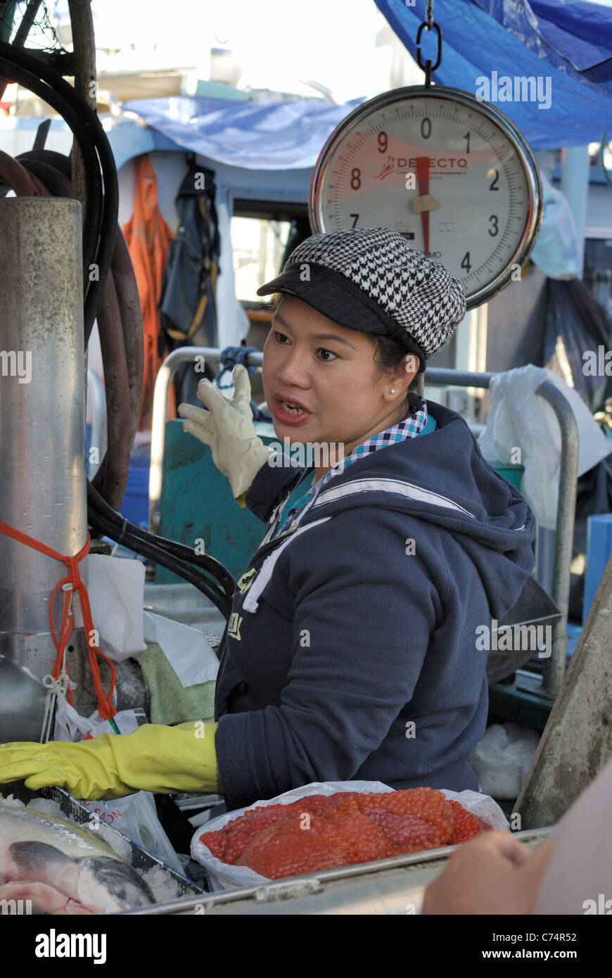 Commercial fish monger in the act of selling fresh fish at the Steveston fish market. Stock Photo