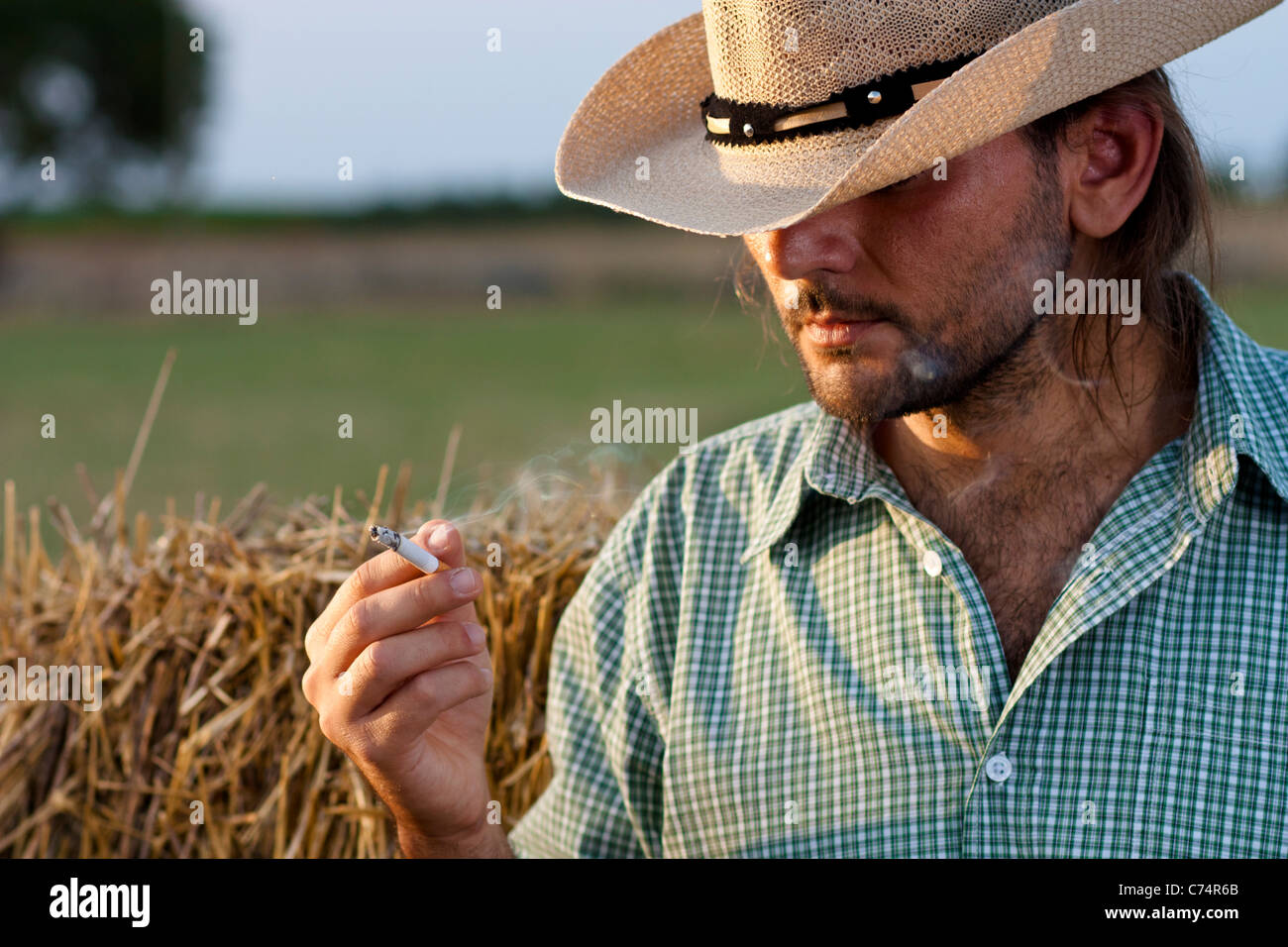 Cowboy with Hay Bale Smoking a Cigarette Stock Photo