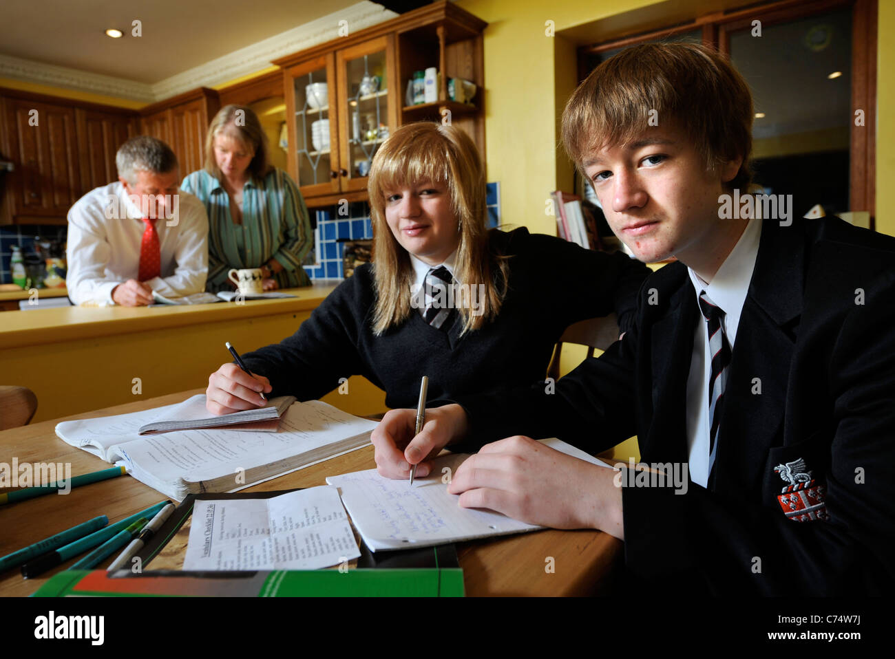 Parents watch as school children do their homework UK Stock Photo
