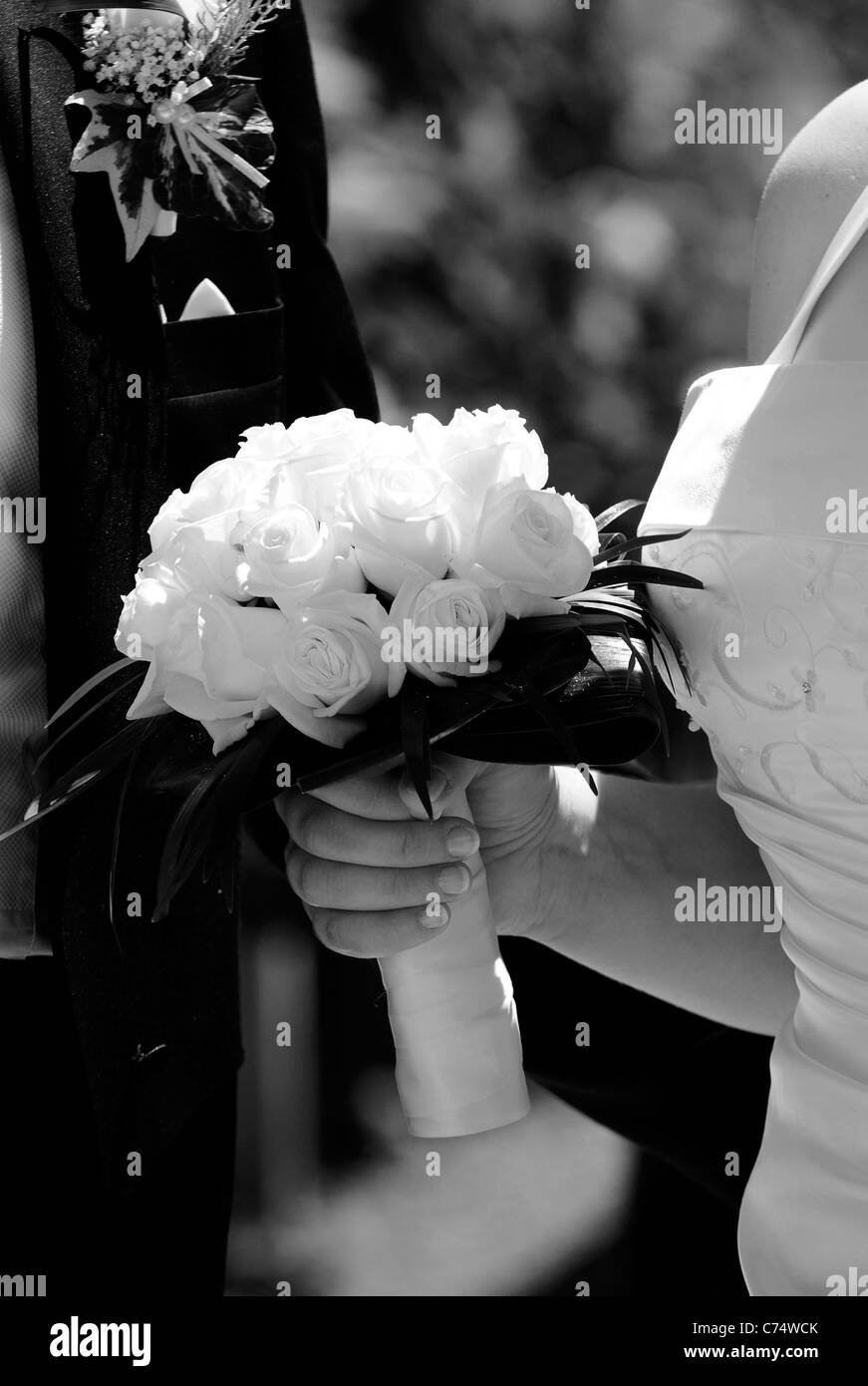 Detail of the bride and groom with boquet of roses in black and white. Stock Photo