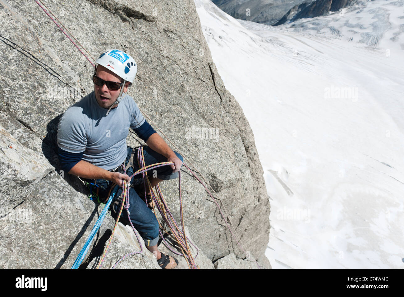 A rock climber belaying high above the Vallee Blanche glacier in Chamonix, France. Stock Photo