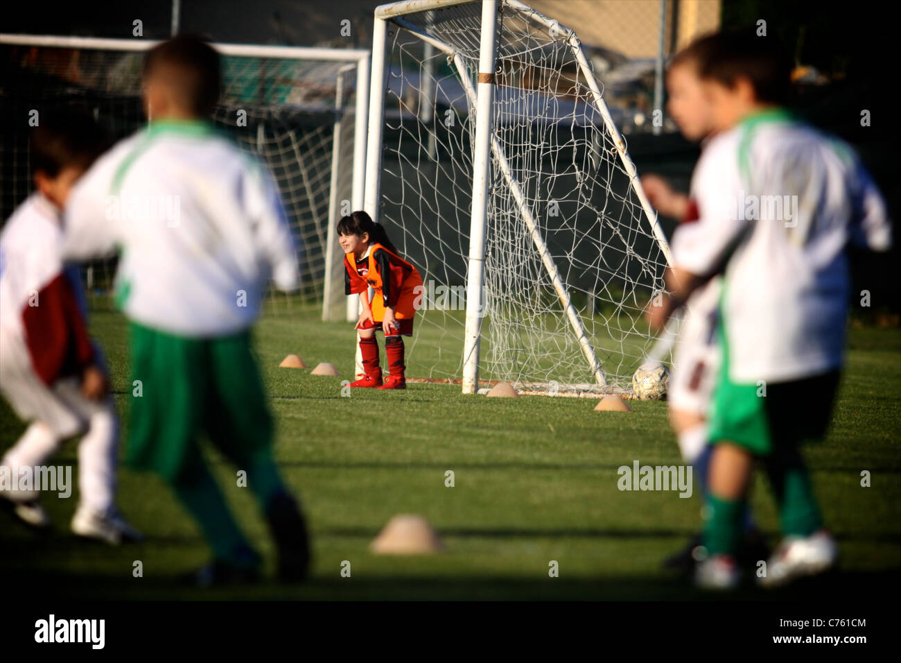 little soccer goalkeeper girl standing on the front of the goal waiting