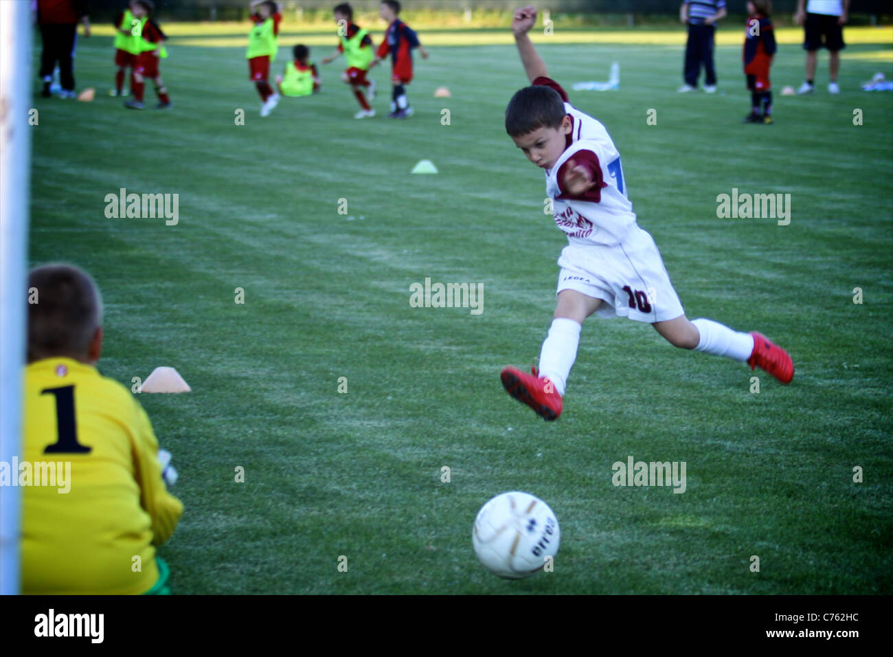 kick to goal, the striker kid soccer player is kicking strong, but the