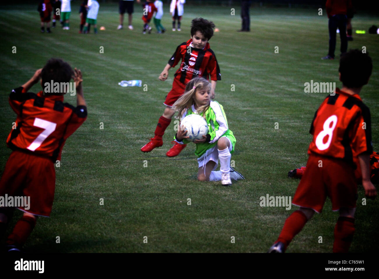 Little goalkeeper girl get the ball in the middle of three opponents