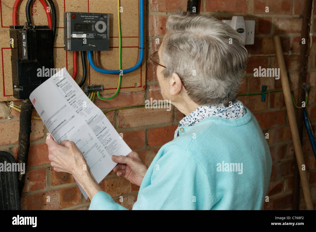 elderly woman looking & checking electricity and gas utility bills with the meter in case of discrepancies Stock Photo