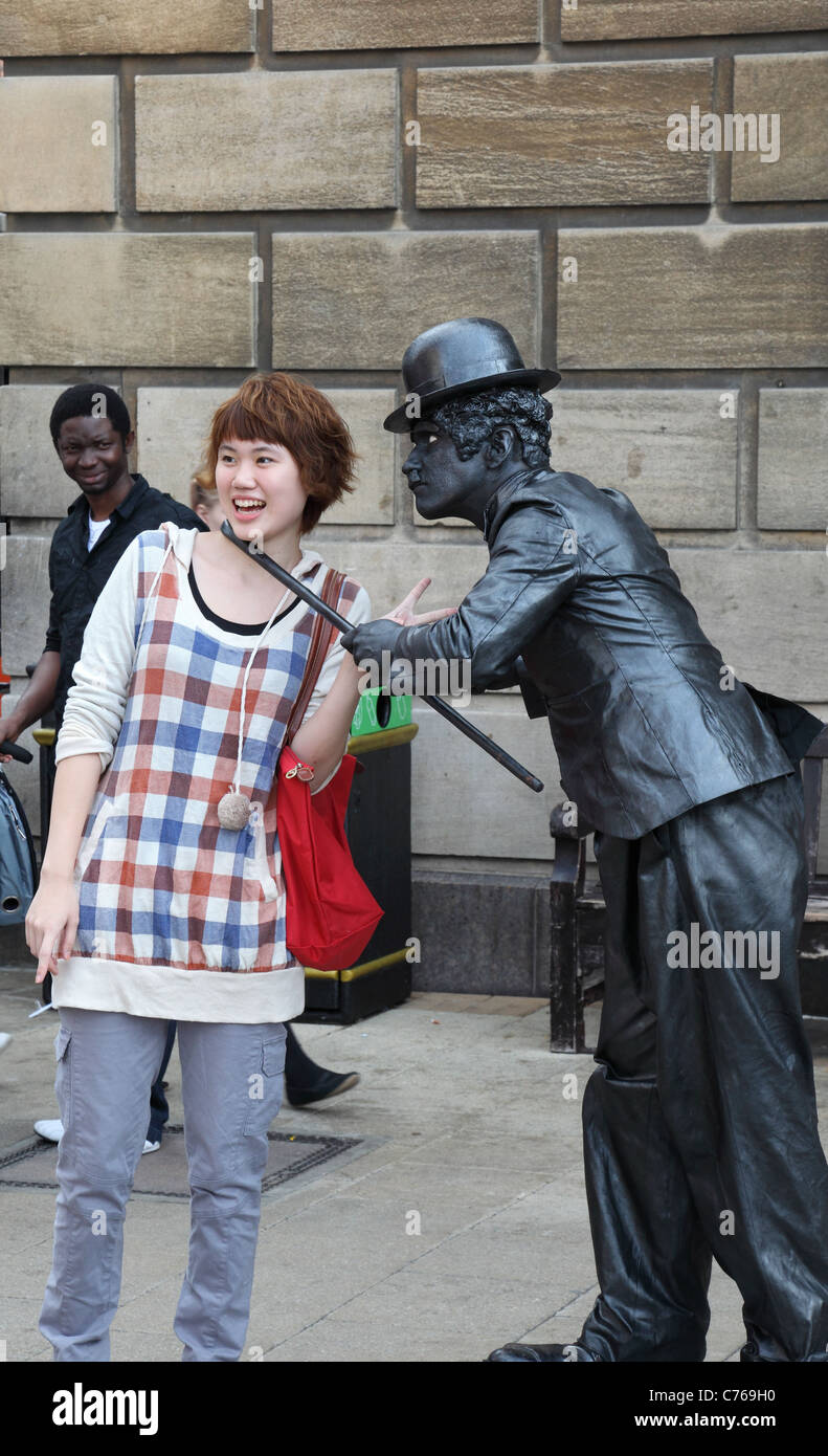 Chaplinesque street performer interacting with member of audience Stock Photo
