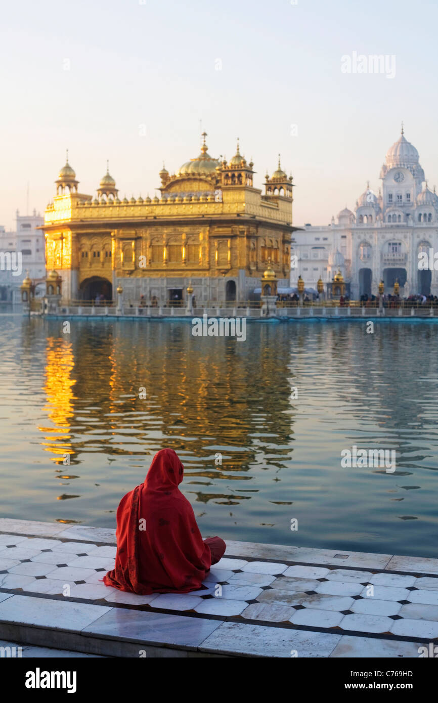 A woman sits by the side of the lake at the Sikh Golden Temple in Amritsar, India in Punjab state Stock Photo