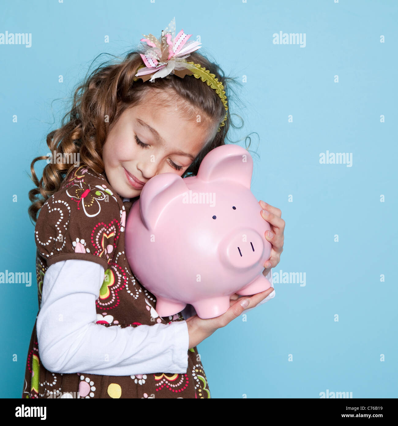 Girl (8-9) embracing piggybank, studio shot Stock Photo