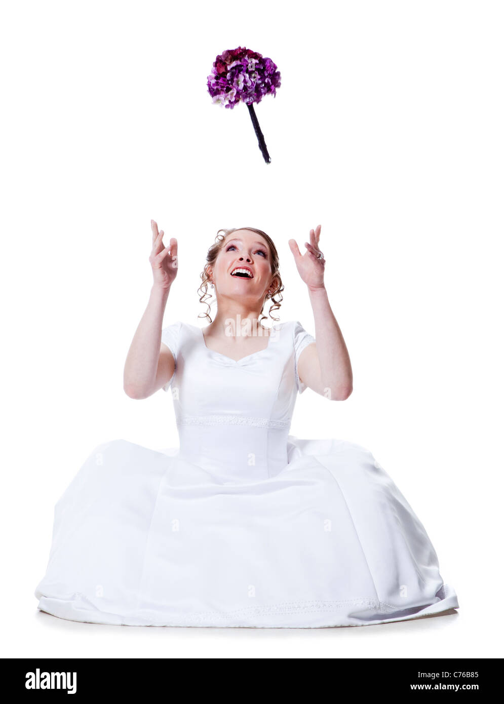 Happy bride throwing bouquet, studio shot Stock Photo
