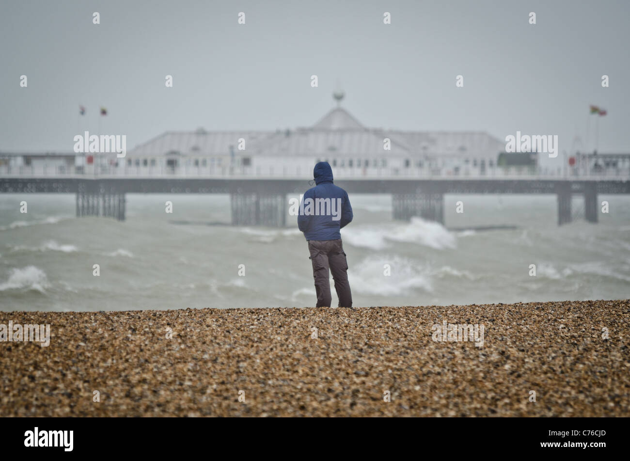 A man watches gale force winds bring huge waves to the seafront at Brighton, East Sussex. Stock Photo