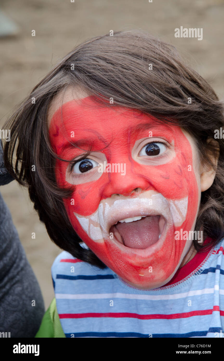close up of surprised looking boy with red and white face paint Stock Photo