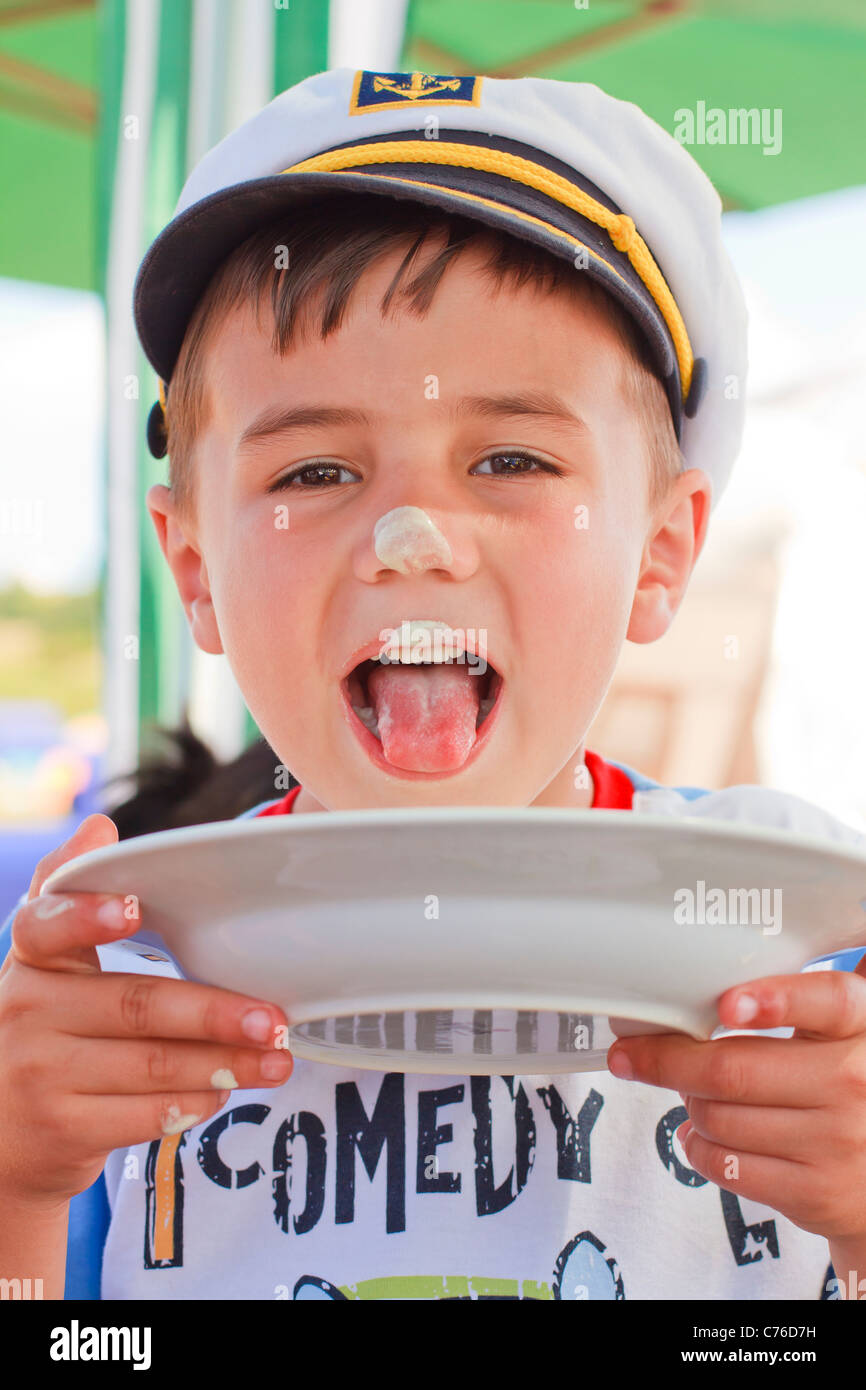 Sailor little boy licking a plate Stock Photo