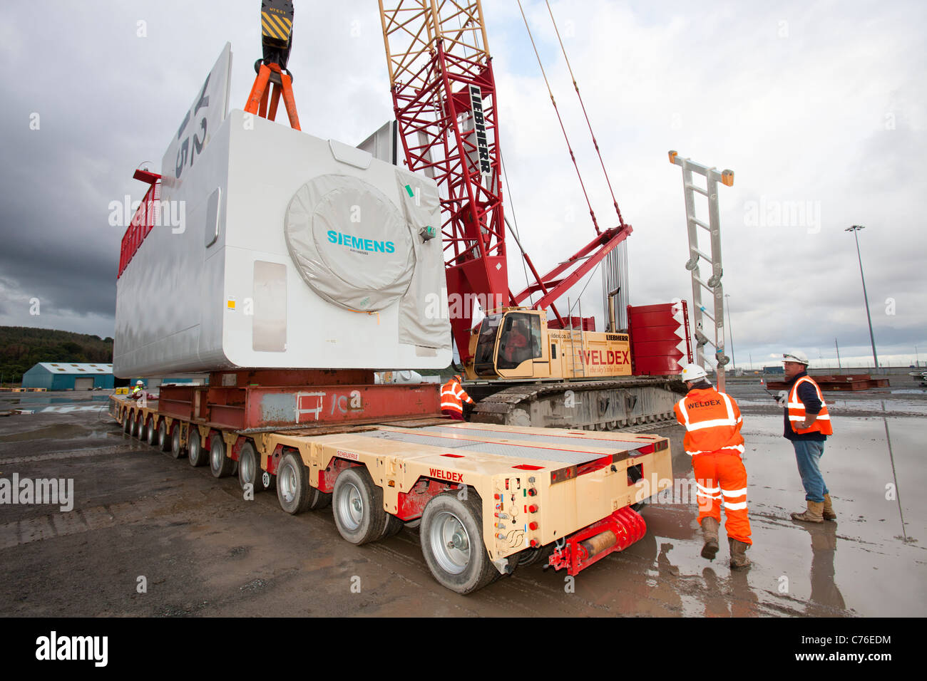 Workers lift a nacelle for a wind turbine onto a jack up barge, for the Walney offshore wind