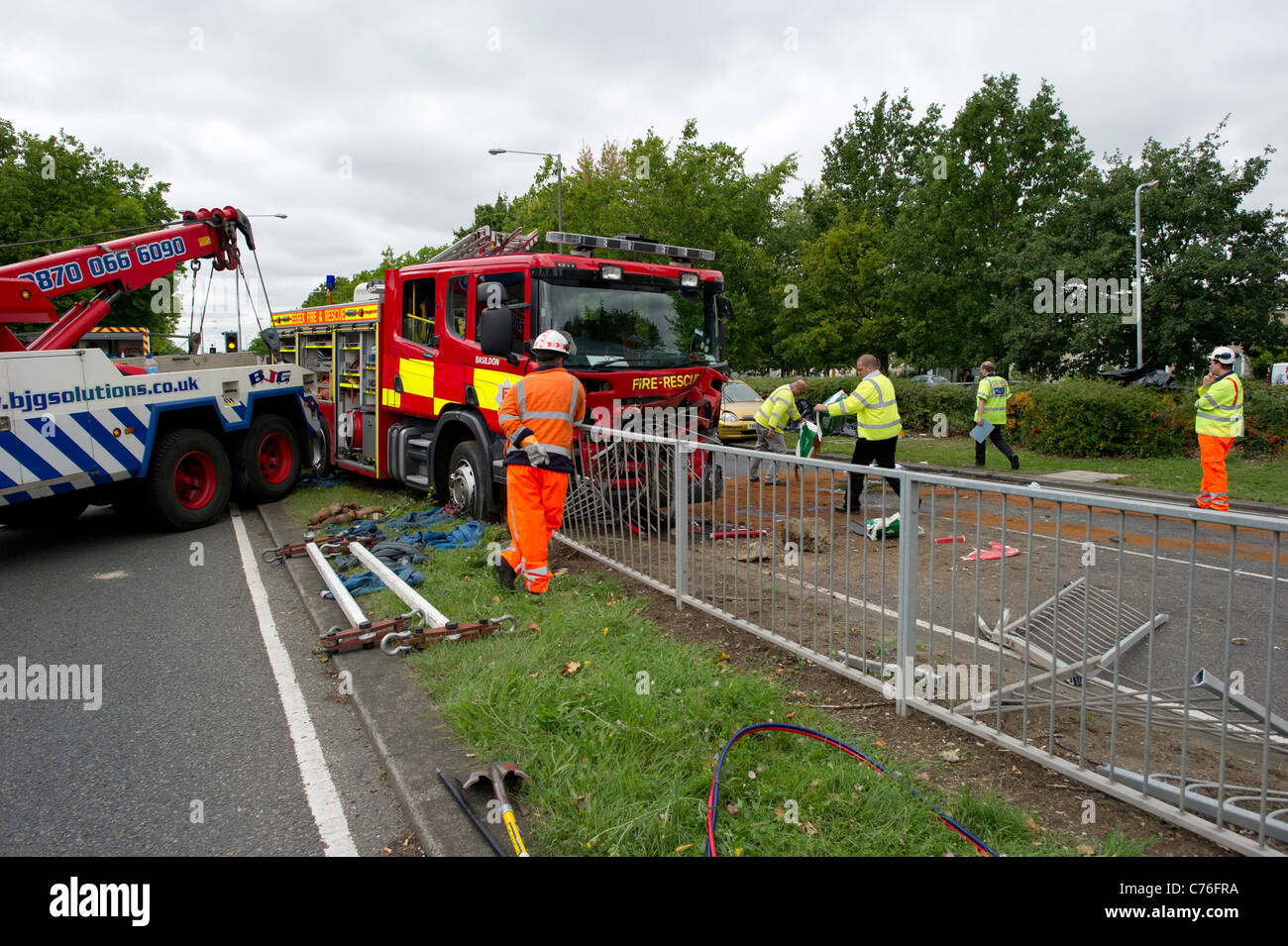 Police and recovery workers preparing to clear the scene of a serious road accident involving a fire engine and a car. Stock Photo