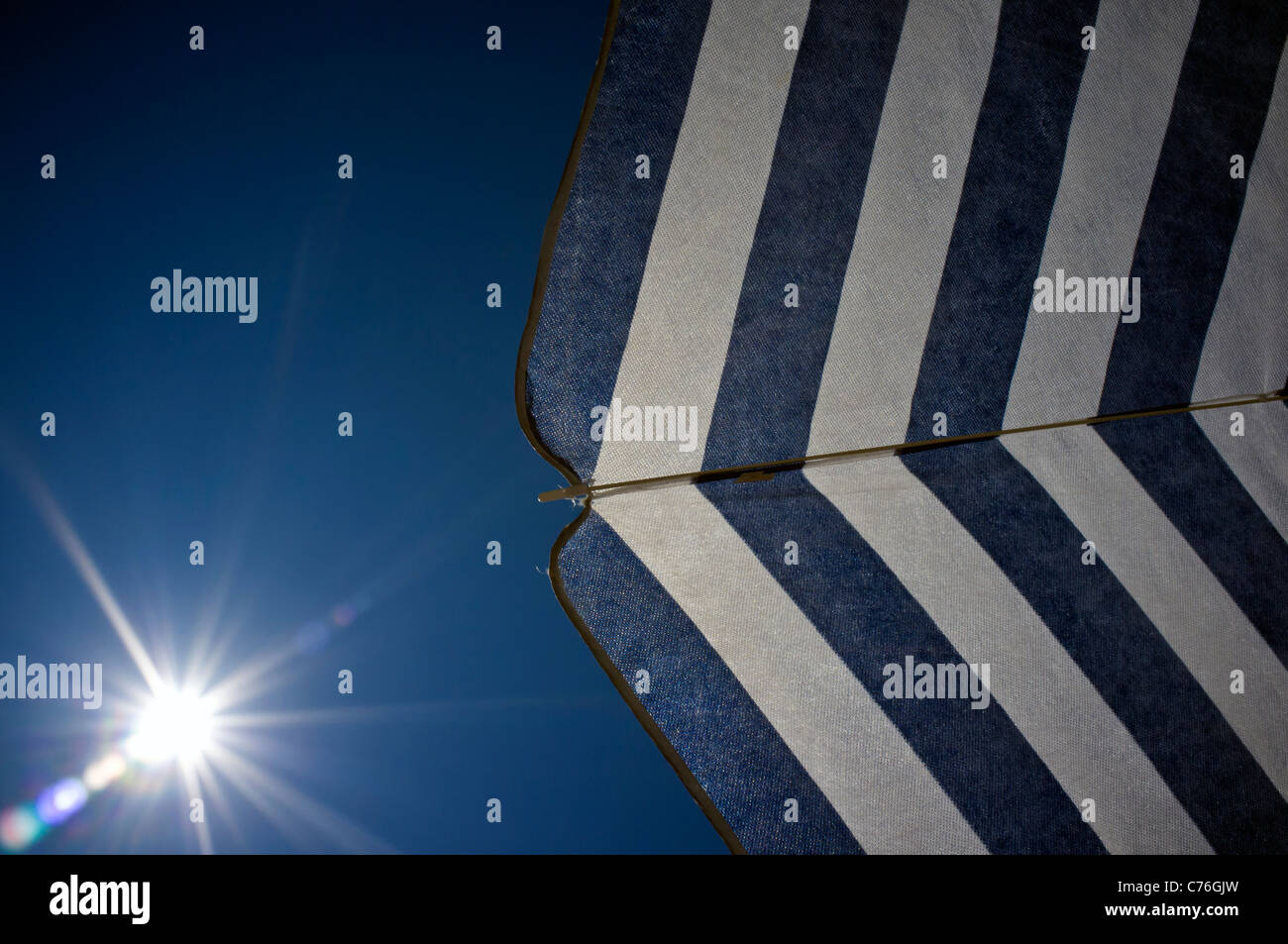 Under a blue and white stripped parasol umbrella Stock Photo