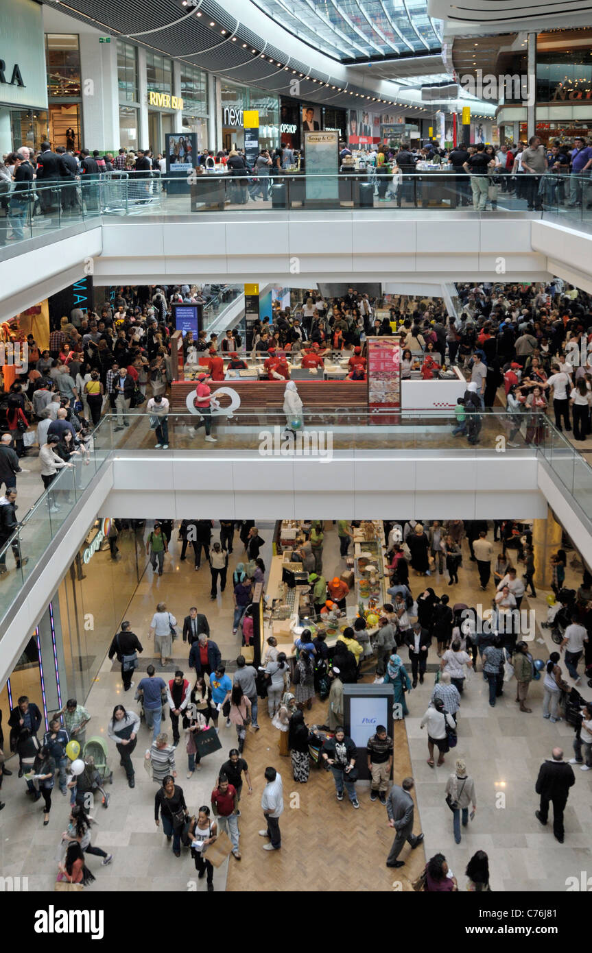 View from above looking down on busy crowd of people on three levels malls interior at Stratford City Westfield shopping centre East London England UK Stock Photo