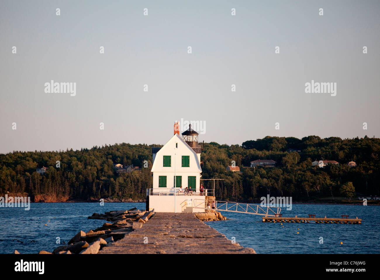 A lighthouse sits at the edge of a large, rocky dyke. Stock Photo