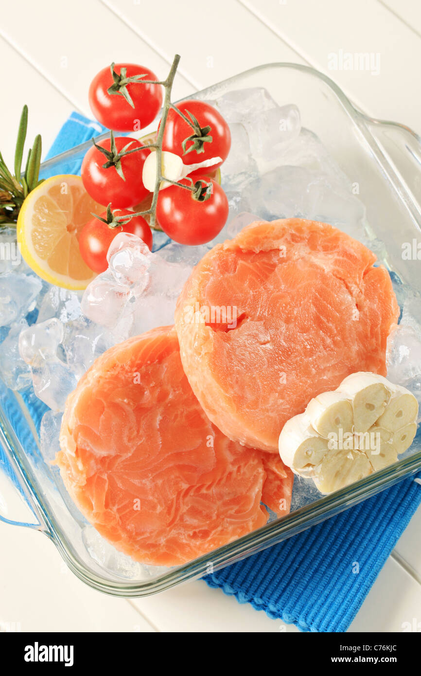 Raw salmon patties and other ingredients on ice Stock Photo