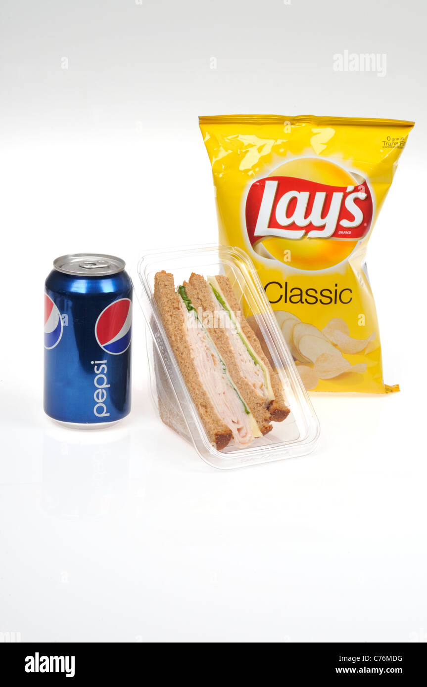 Takeaway lunch with Turkey and cheese on whole wheat bread sandwich packet, Lay's potato chips and Pepsi can on white background. Stock Photo