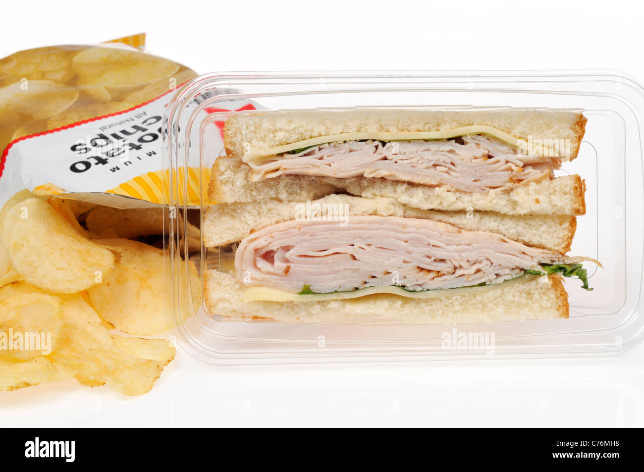 Prepared turkey and cheese take away sandwich in plastic pack with bag of crisps or potato chips on white background. Stock Photo