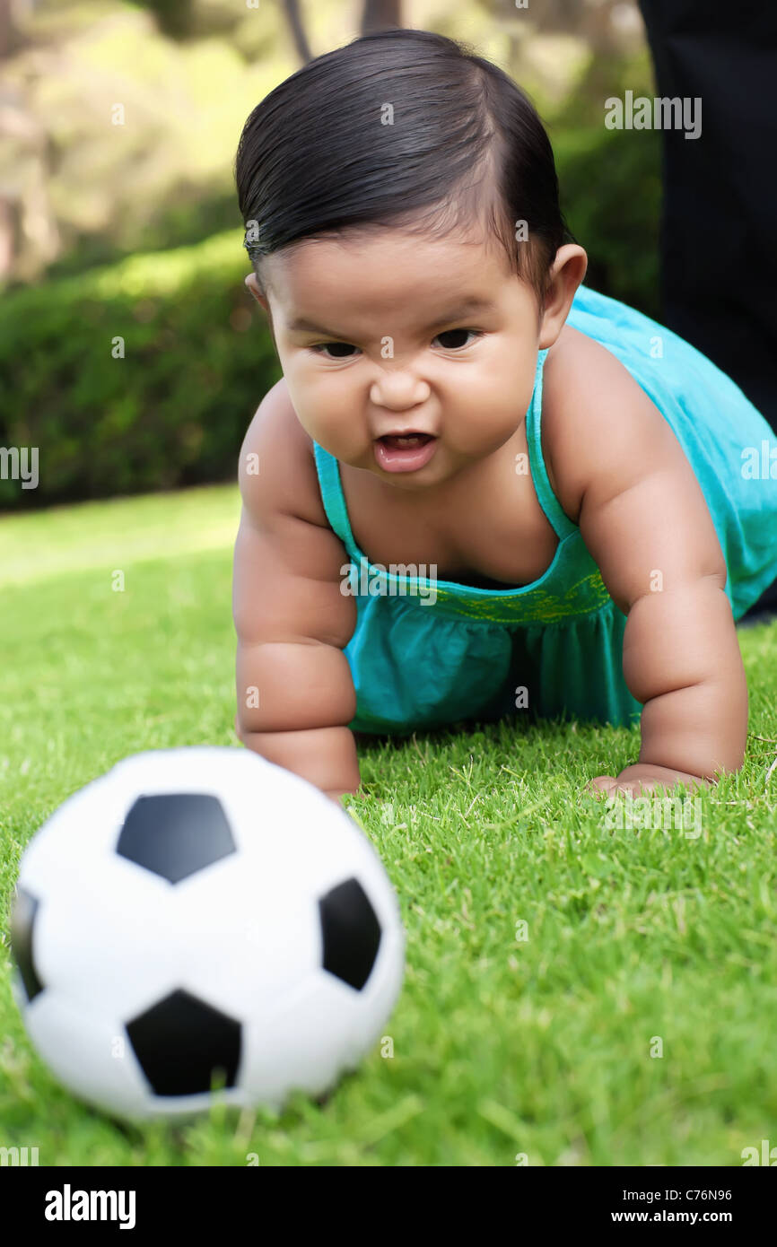 Little girl playing with a soccer ball in a park supporting her own